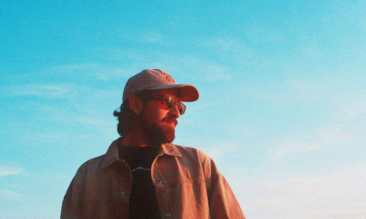 Frah Quintale indossa il suo classico cappello su uno sfondo di un cielo azzurro