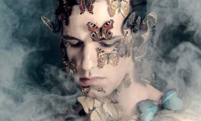 Achille Lauro con farfalle sul viso avvolto dal fumo, immagine promozionale dell'album Comuni Immortali