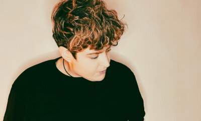 Ritratto della cantautrice Annarè con lo sguardo rivolto verso il basso, su sfondo dalle tonalità calde.