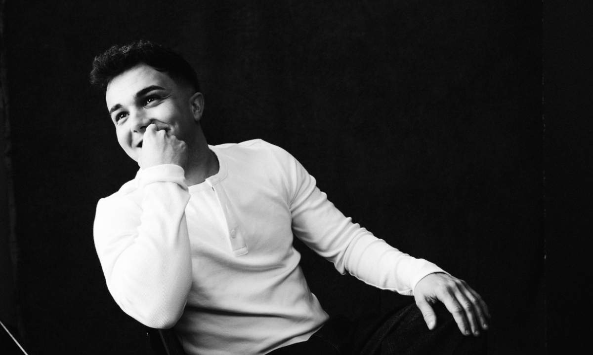 Juli in una foto in bianco e nero con maglia bianca, seduto e sorridente