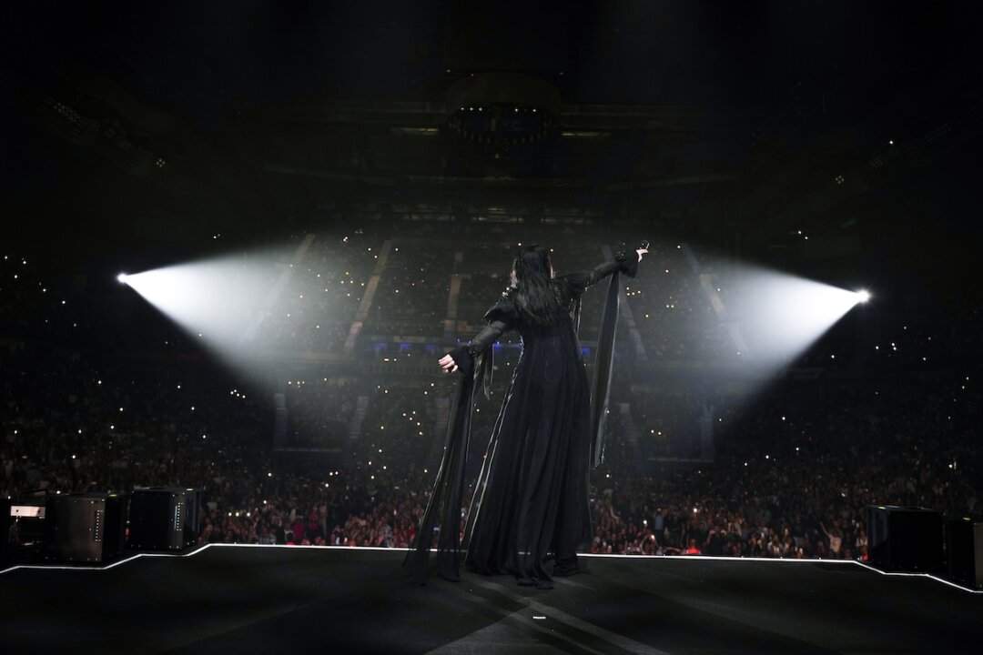 Laura Pausini di spalle sul palco di Madrid con le braccia aperte e il palasport sold out illuminato dai cellulari del pubblico