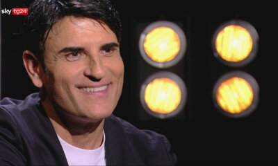 Sal Da Vinci sorridente durante l'intervista a Stories di Sky TG24, con faretti arancioni sullo sfondo