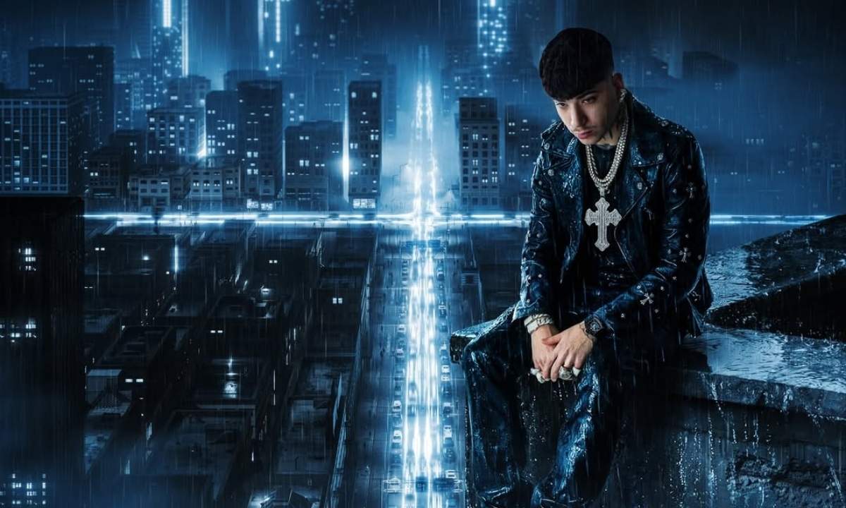 Shiva seduto su un cornicione con lo skyline di una città notturna sotto la pioggia, giacca di pelle nera e collana con croce