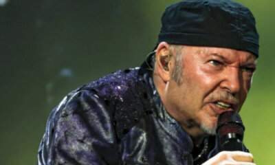 Vasco Rossi sul palco con microfono e bandana nera durante un concerto live
