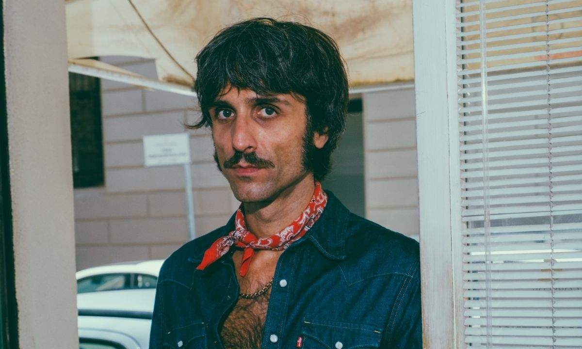 Primo piano di Cristiano Sbolci con camicia di jeans e bandana rossa per il lancio del disco "Fuorimoda"