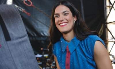 Bambina sorride dietro le quinte del palco di 1MNEXT 2026, indossa una blusa blu a pois bianchi e cravattino bordeaux