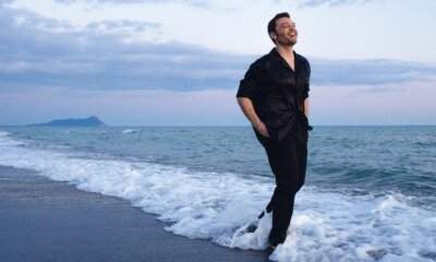 Tiziano Ferro fotografato sulla riva del mare per il lancio di Sono un grande Deluxe e le dichiarazioni su Sanremo