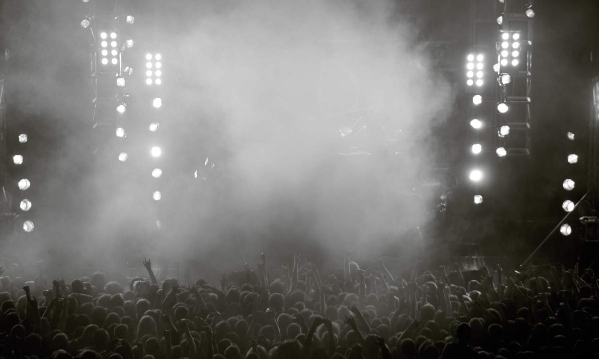 folla a un concerto con palco illuminato e fumo, immagine di repertorio