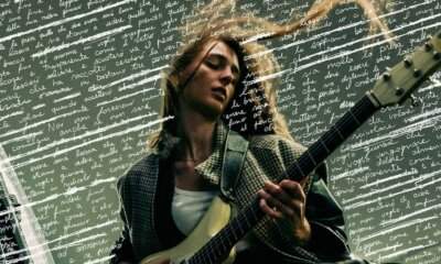 Emma Nolde con la chitarra davanti ai versi manoscritti di Quello che deve essere sarà