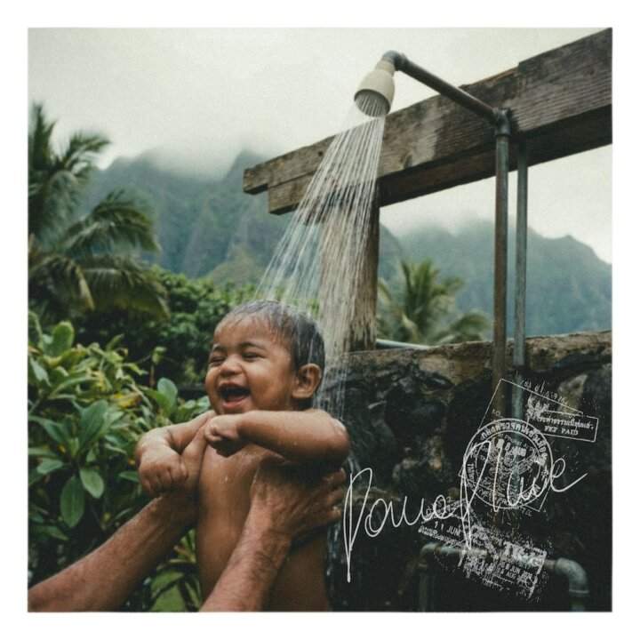 Copertina del singolo Parapluie di Rhove, un bambino sorride sotto una doccia all'aperto in un paesaggio tropicale