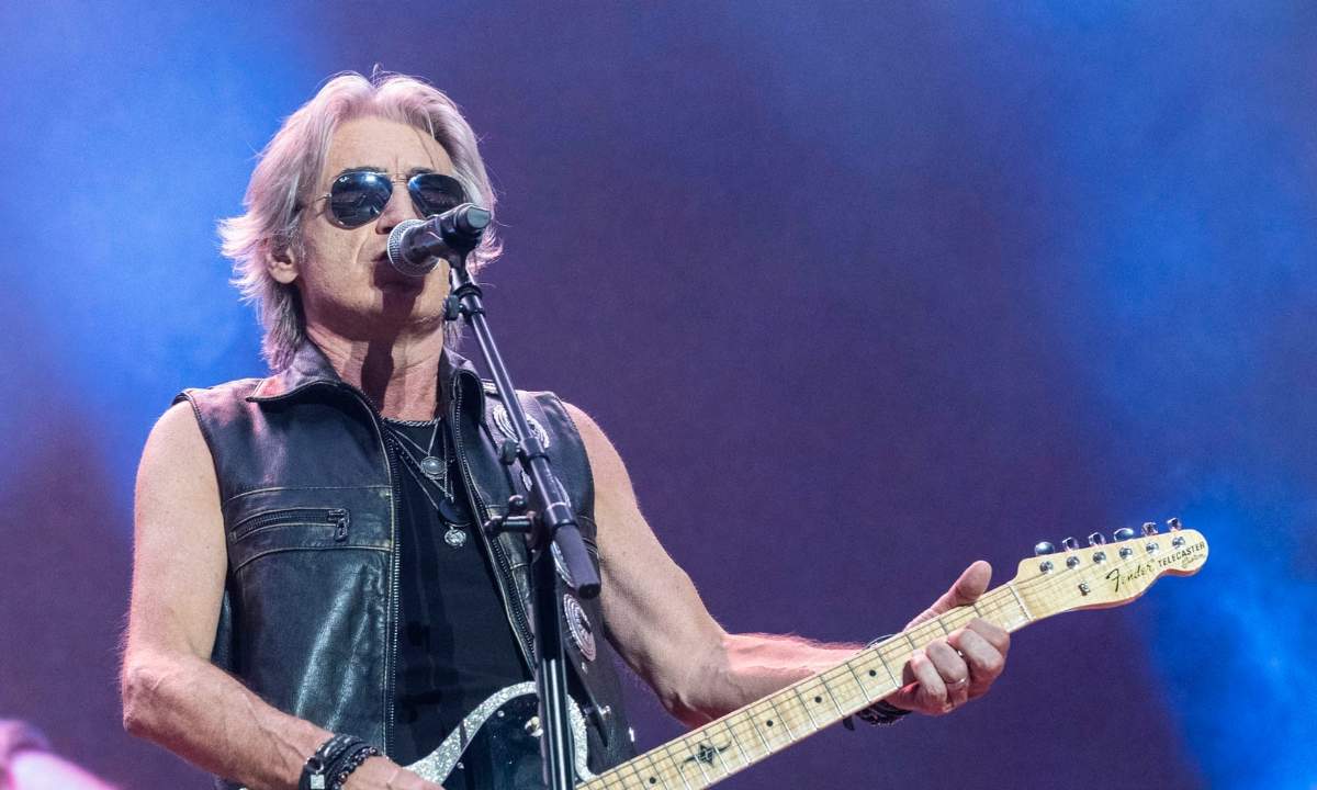 Ligabue sul palco con la chitarra durante un concerto, luci blu sullo sfondo