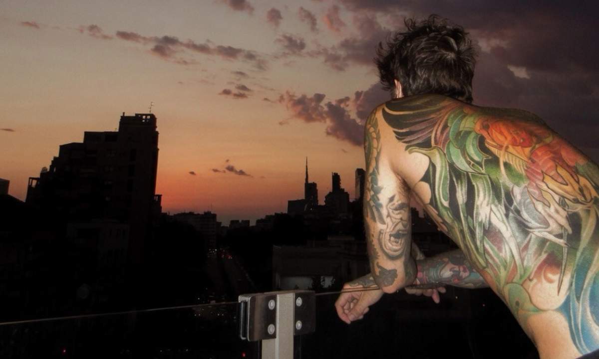 Fedez di spalle al tramonto su un terrazzo a Milano nel giorno del messaggio dopo il ricovero