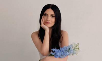 Laura Pausini seduta con un mazzo di delphinium azzurri in uno degli scatti pubblicati con la data 7.8.2026