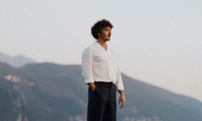 Luca Tudisca in camicia bianca su un promontorio, con le montagne sullo sfondo