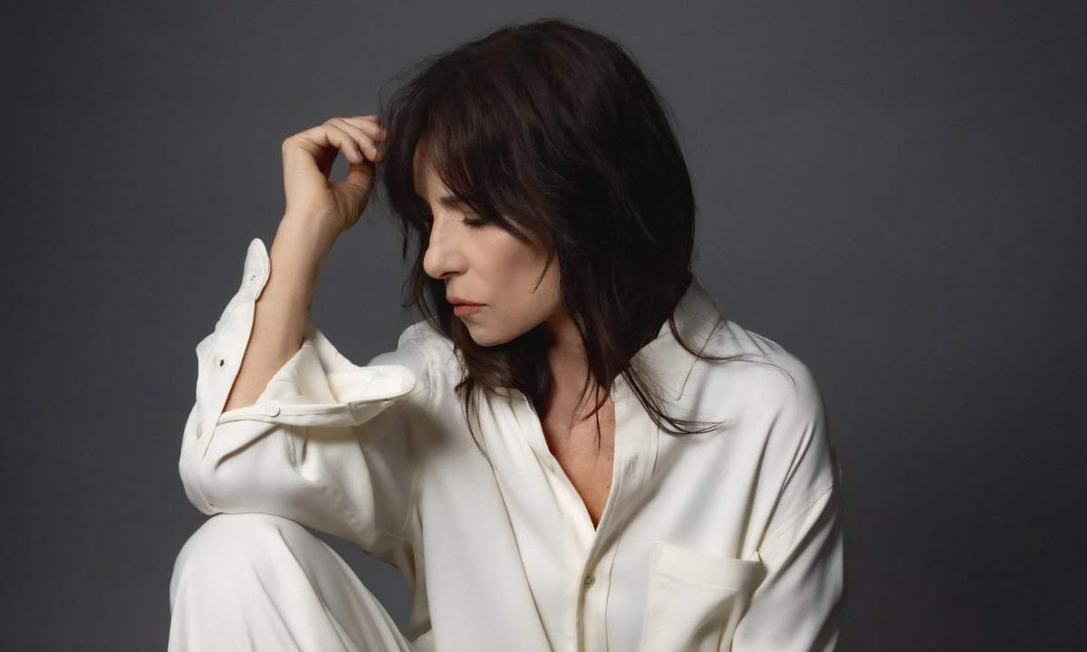 Paola Turci seduta con camicia bianca su fondo grigio, foto per il singolo Manchi