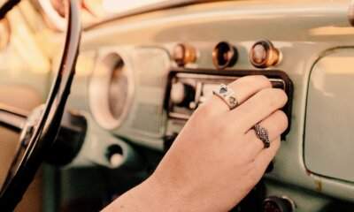 Quanto paga un passaggio in radio: una mano sintonizza l'autoradio di un'auto d'epoca alla luce del tramonto