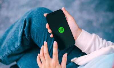 Una ragazza apre l'app di Spotify sullo smartphone: il logo verde sullo schermo del telefono
