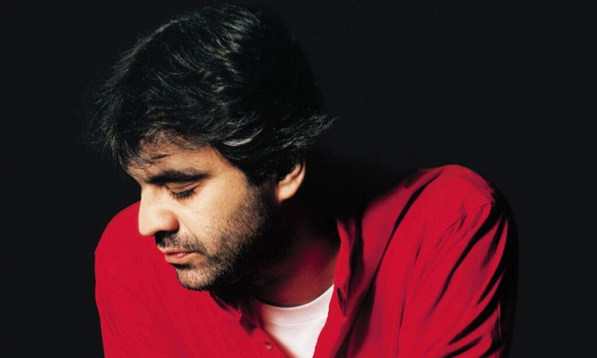 Andrea Bocelli con camicia rossa su fondo nero, ritratto degli anni di Con te partirò e dell'album Bocelli