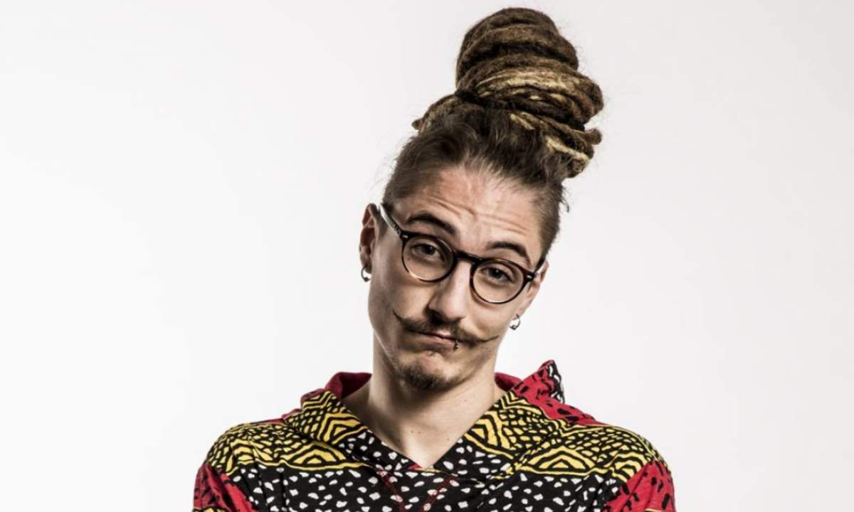 Cranio Randagio, il rapper Vittorio Andrei, in una foto su fondo bianco con i dreadlocks raccolti e la felpa a stampa colorata
