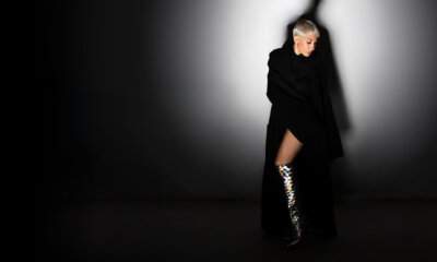 Malika Ayane in una foto promozionale per il tour A Teatro 2026, con cappotto nero e stivali metallizzati