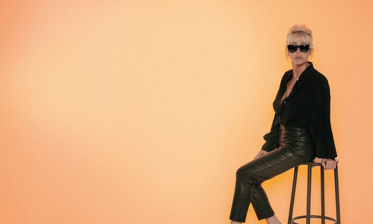 Malika Ayane in una foto promozionale per l'album Cicale, seduta su uno sgabello con abito nero e occhiali da sole