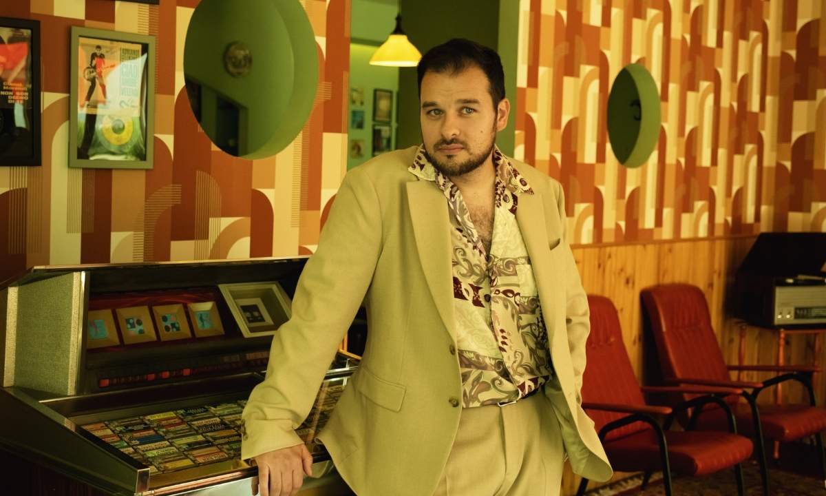 Napoleone (Davide Napoleone) accanto a un jukebox in un'ambientazione vintage anni '70