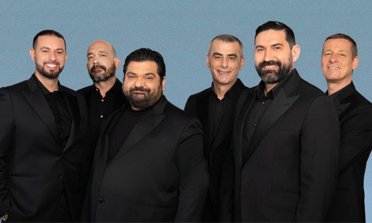 I sei componenti dei Neri per Caso vestiti di nero su fondo azzurro, la formazione attuale del gruppo a cappella