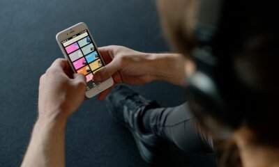 Utente con cuffie sfoglia le playlist di Spotify dallo smartphone, dove arriva il badge AI Persona