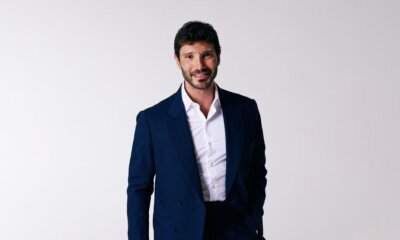 Stefano De Martino, direttore artistico di Sanremo Giovani 2026, sorride in giacca blu su sfondo neutro