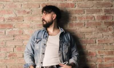 Filippo Graziani in un ritratto con giacca di jeans su un muro di mattoni