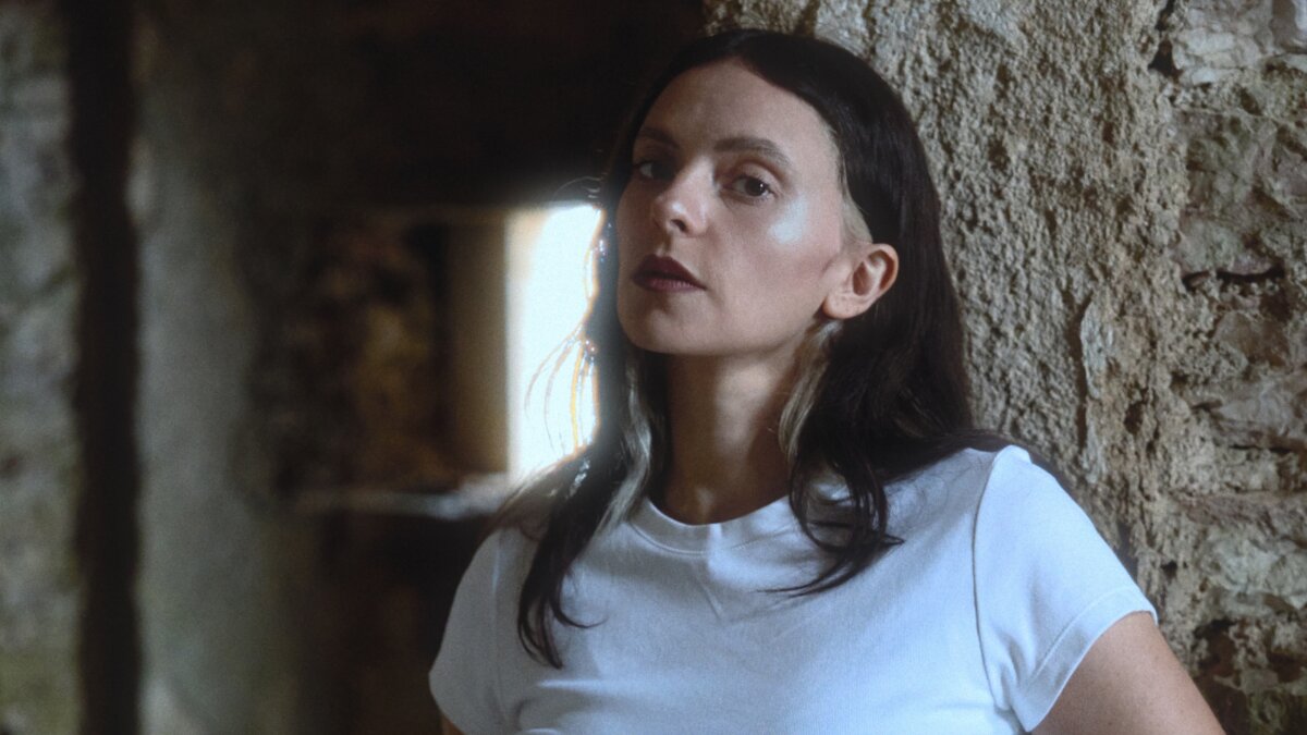 Francesca Michielin con una maglietta bianca accanto a una parete di pietra