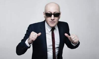 Giuliano Palma con occhiali da sole scuri e completo blu, foto promozionale per il concerto con The Bluebeaters a Milano