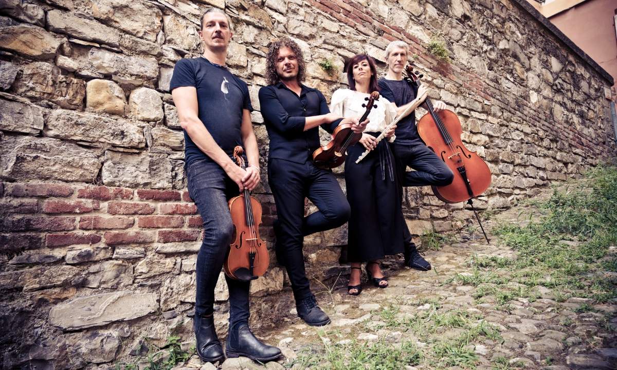 I quattro GnuQuartet con violino, viola, flauto e violoncello davanti a un muro di pietra