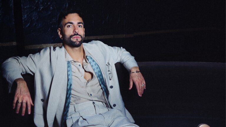 Marco Mengoni in giacca chiara seduto su un divano, per Allo Sbagliato a Milano