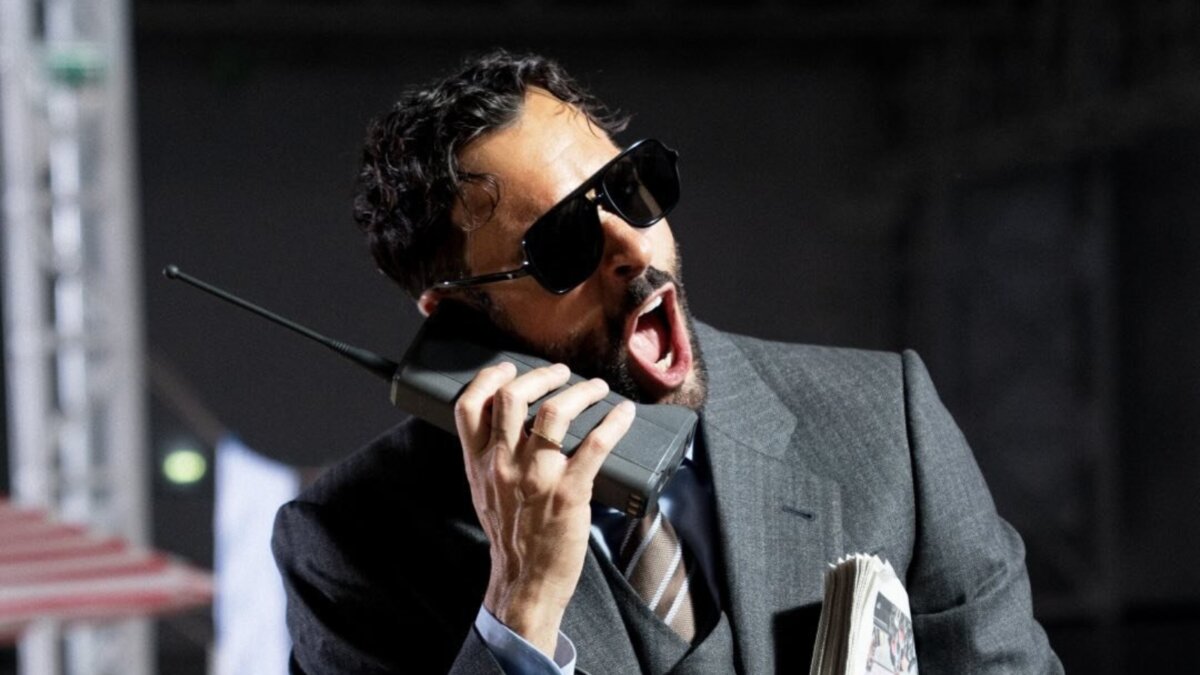 Marco Mengoni con occhiali da sole mentre parla a un telefono portatile