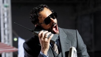 Marco Mengoni con occhiali da sole mentre parla a un telefono portatile