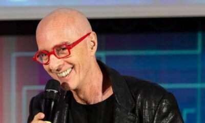 Massimo Cotto con microfono e occhiali rossi