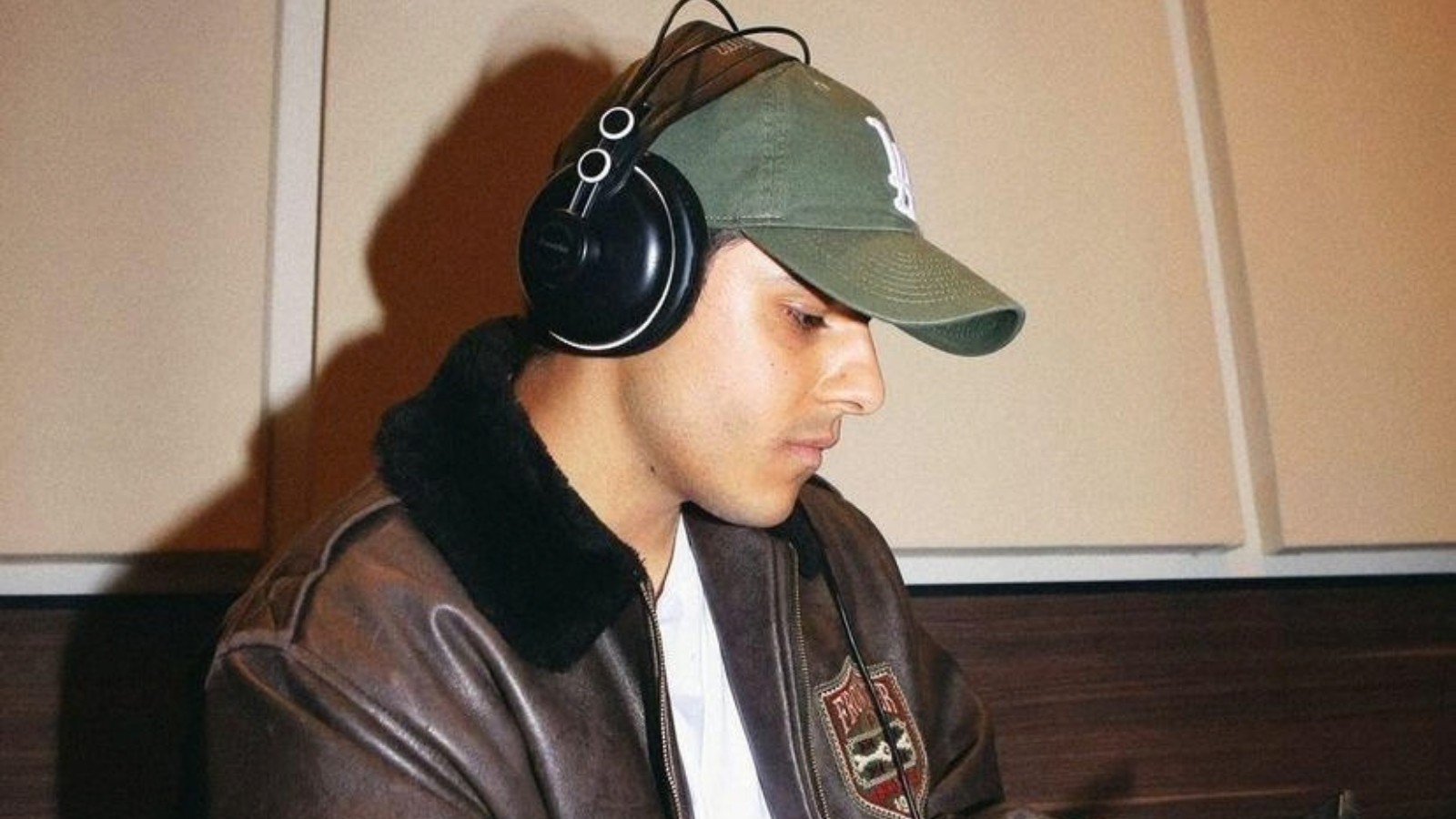 Michele Merlo, il cantautore uscito da Amici, in studio con le cuffie e un cappellino verde