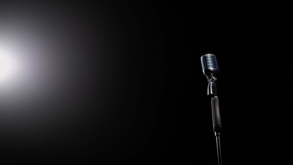 Un microfono da studio illuminato su fondo nero, immagine simbolica della vertenza dei musicisti americani.