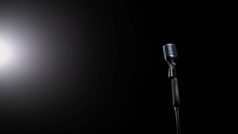 Un microfono da studio illuminato su fondo nero, immagine simbolica della vertenza dei musicisti americani.