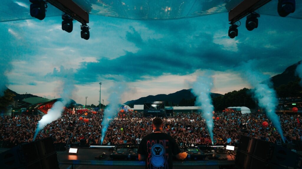 Nameless Festival al Bione di Lecco: il pubblico sotto il palco durante un dj set, con i getti di fumo e le montagne sullo sfondo