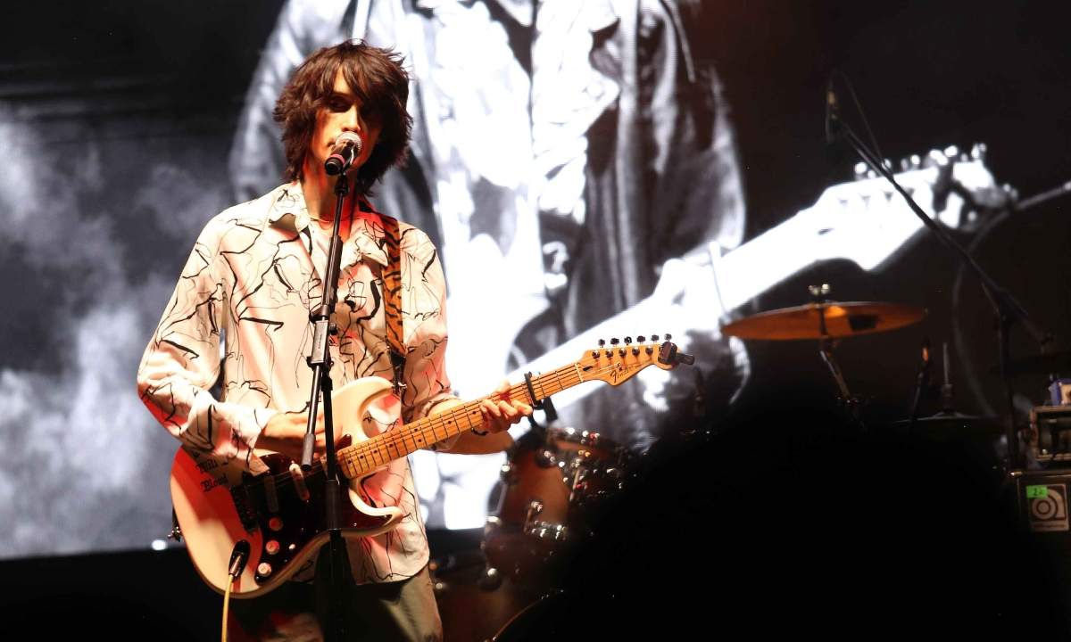 Nicola Ferrari canta al microfono con la chitarra elettrica sul palco