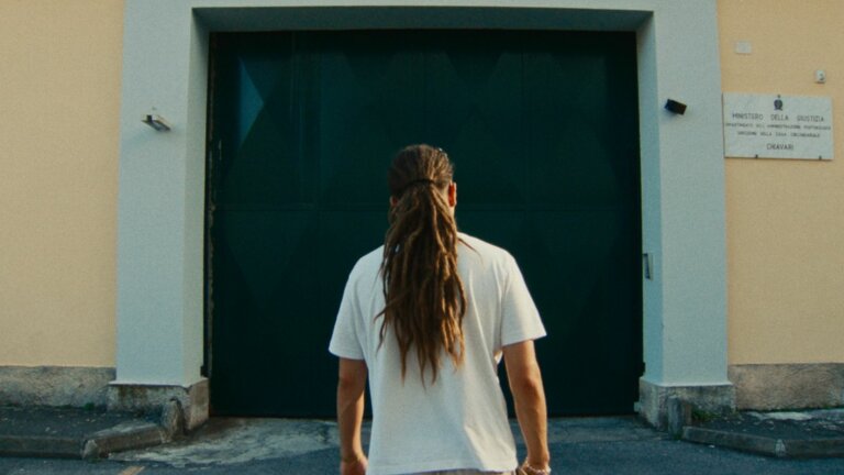 Sayf di spalle davanti al portone del carcere di Chiavari, in una scena del documentario Il cielo in una stanza