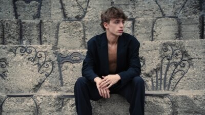 ALTEO seduto su una gradinata di pietra, nella foto promozionale del singolo Iride