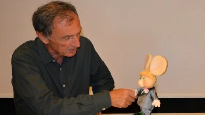 Andrea Rosi, presidente e CEO di Sony Music Italy, stringe la mano a Topo Gigio nella foto della firma con l'etichetta