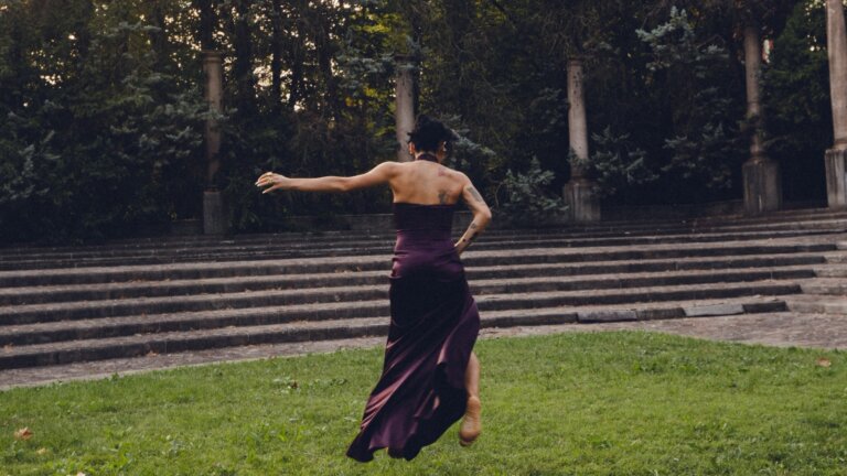 Angelina Mango di spalle, in movimento e con un abito viola scuro, in un parco davanti a una gradinata, nell'immagine che annuncia il singolo Vita da adulti