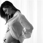 Anna Tatangelo, ospite di Verissimo con il figlio Andrea, in una foto in bianco e nero con la mano sul pancione dal suo profilo Instagram