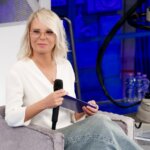 Maria De Filippi in poltrona con il microfono nello studio di Amici 26, nella foto di scena della nuova edizione