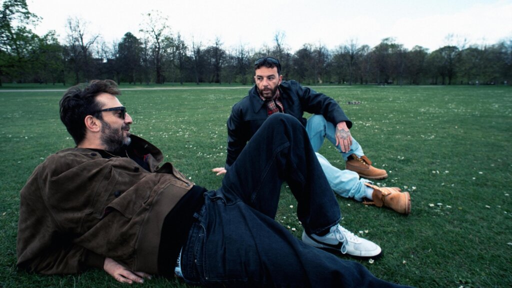 Cesare Cremonini e Salmo seduti sull'erba a Hyde Park, a Londra, durante la lavorazione di AMATEUR