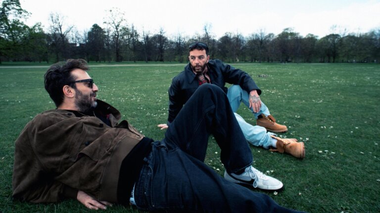 Cesare Cremonini e Salmo seduti sull'erba a Hyde Park, a Londra, durante la lavorazione di AMATEUR